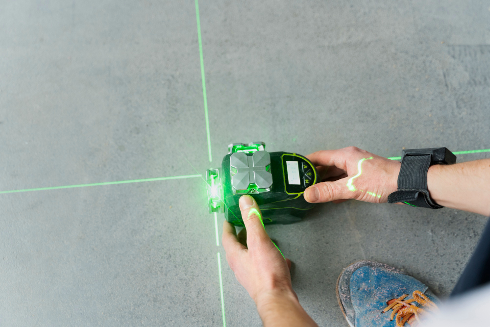 Osoba używa poziomicy laserowej do pomiaru linii na ścianie.