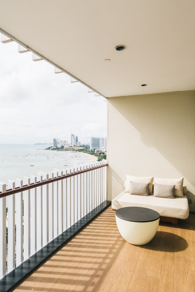 Balkon z kanapą i stołem, z widokiem na ocean w tle.